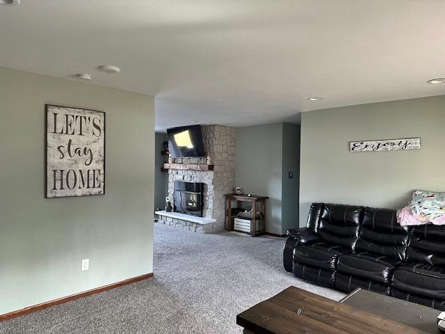 living area featuring baseboards, carpet, and a fireplace