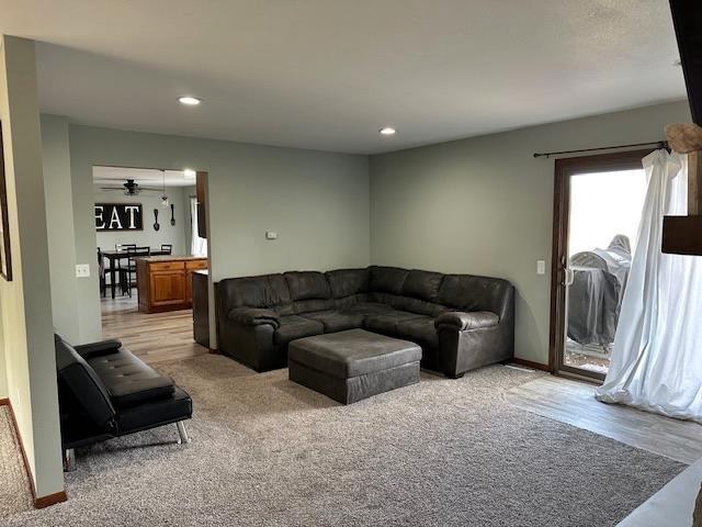 living room featuring recessed lighting, baseboards, and light carpet