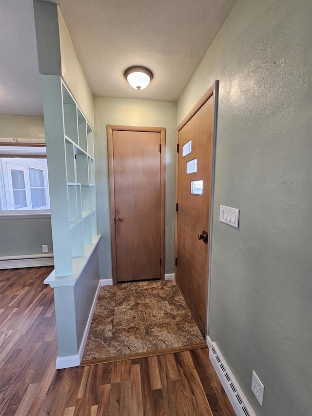 doorway to outside featuring a baseboard radiator, baseboards, and wood finished floors