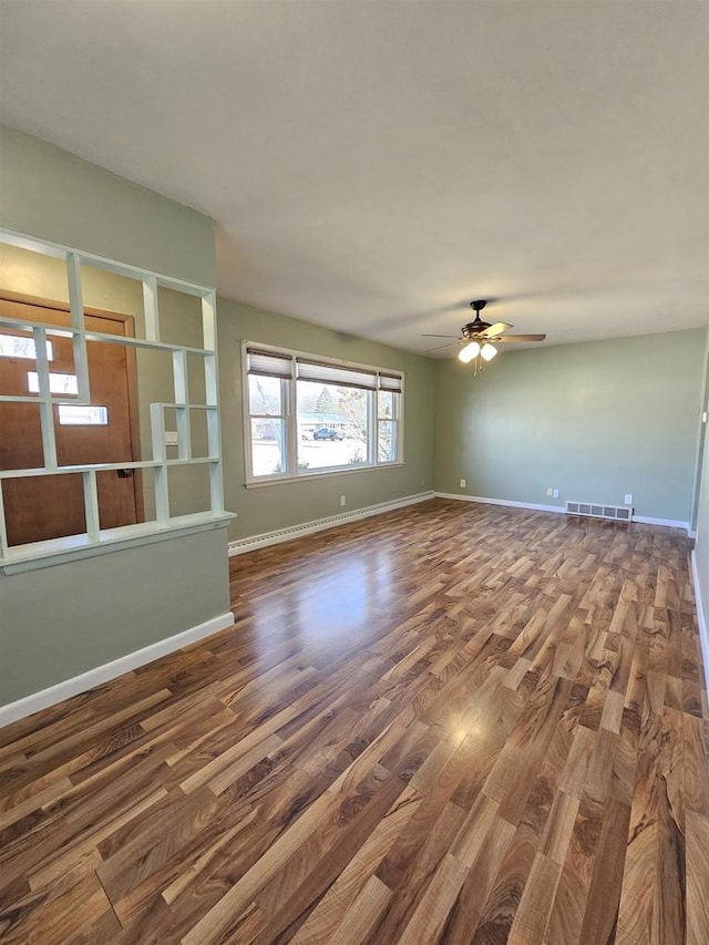 unfurnished living room with ceiling fan, wood finished floors, visible vents, and baseboards