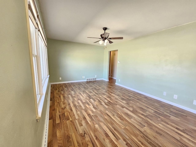 spare room with ceiling fan, wood finished floors, visible vents, and baseboards