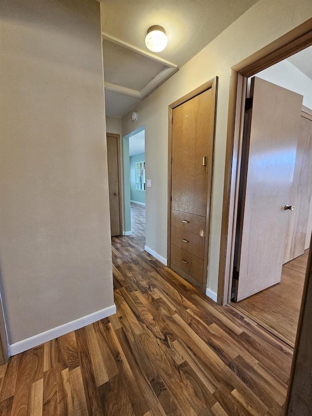 hallway featuring dark wood-type flooring and baseboards