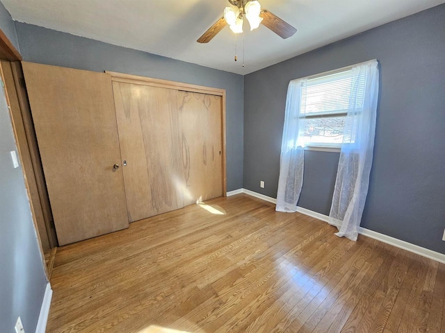 unfurnished bedroom featuring light wood-style flooring, baseboards, a closet, and ceiling fan