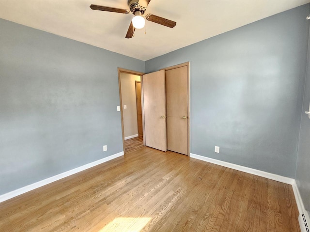 unfurnished bedroom featuring a ceiling fan, light wood-style floors, baseboards, and a baseboard heating unit