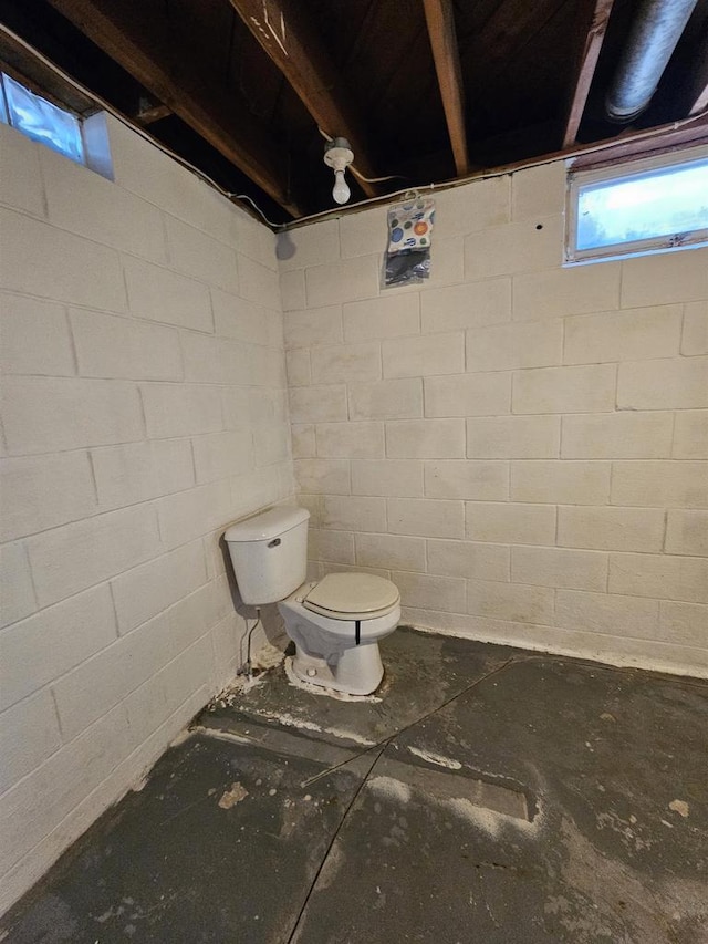 bathroom featuring concrete block wall and toilet