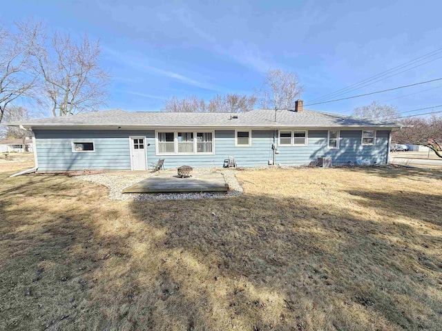 back of house with an outdoor fire pit, a lawn, a chimney, and a patio area