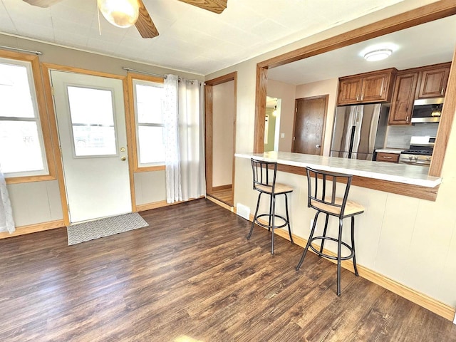 kitchen with dark wood finished floors, a kitchen breakfast bar, stainless steel appliances, and light countertops