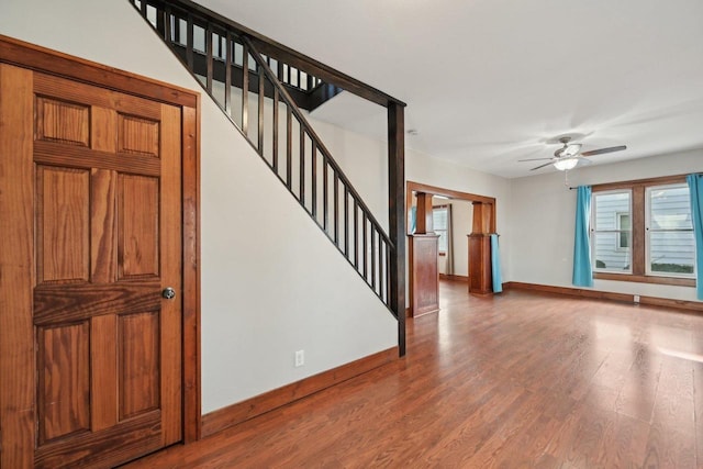 interior space with ceiling fan, baseboards, wood finished floors, and stairs