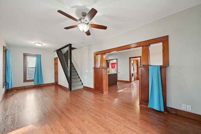 spare room featuring stairway, a ceiling fan, baseboards, and wood finished floors