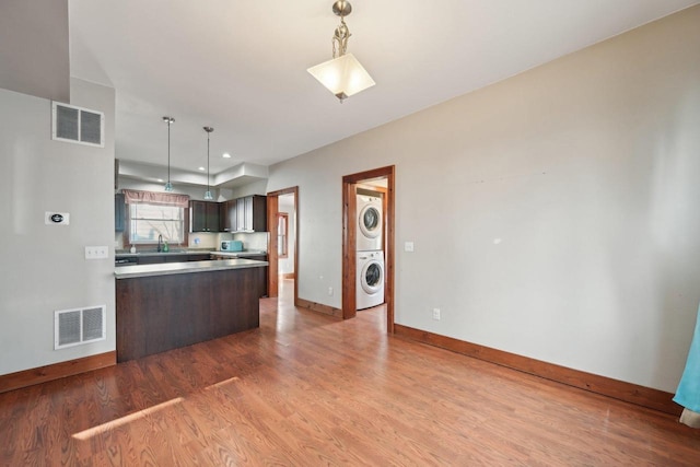 kitchen featuring visible vents, stacked washer / dryer, baseboards, and wood finished floors