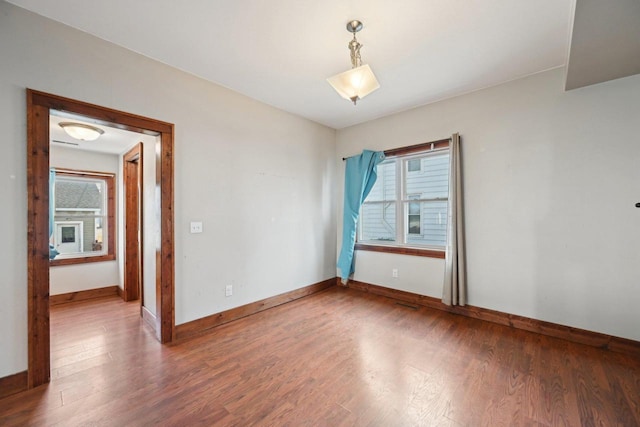 spare room featuring baseboards, a healthy amount of sunlight, and wood finished floors