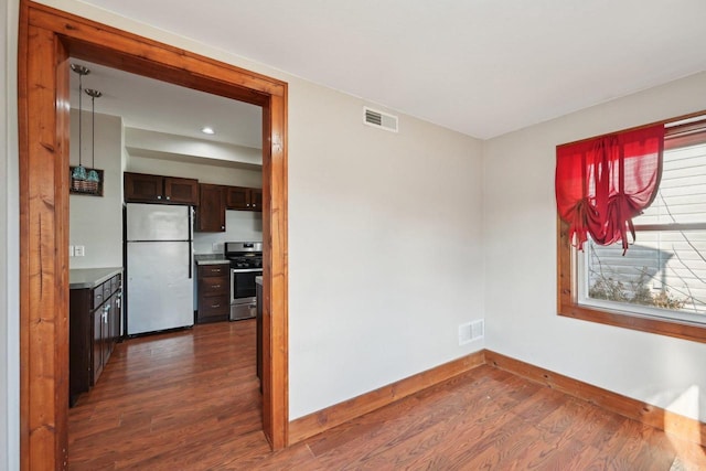 unfurnished room featuring visible vents, baseboards, and dark wood-style flooring