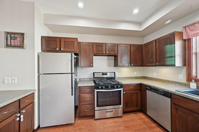 kitchen featuring wood finished floors, recessed lighting, a sink, stainless steel appliances, and light countertops