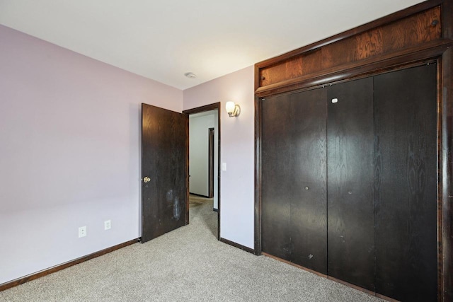 unfurnished bedroom featuring baseboards, a closet, and light carpet