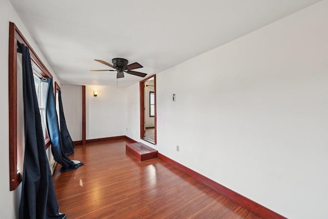 unfurnished room with wood finished floors, baseboards, and ceiling fan