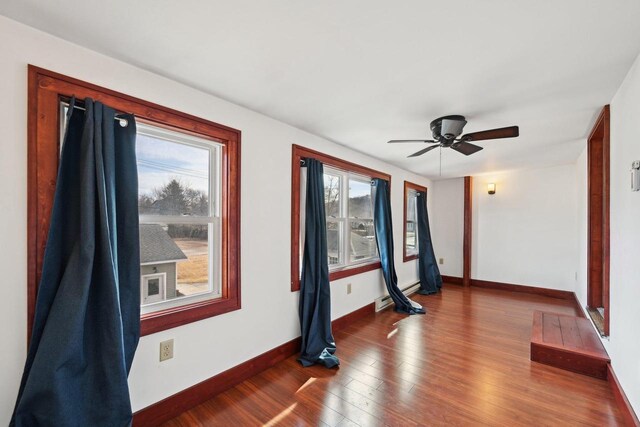 spare room featuring ceiling fan, baseboards, and wood finished floors