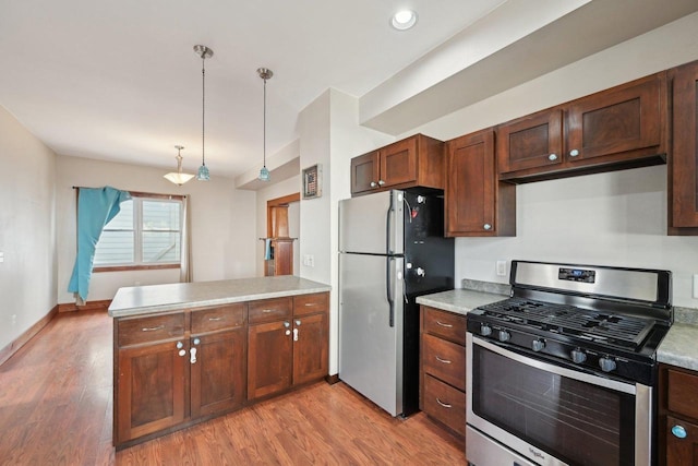 kitchen with a peninsula, light countertops, light wood-type flooring, and stainless steel appliances