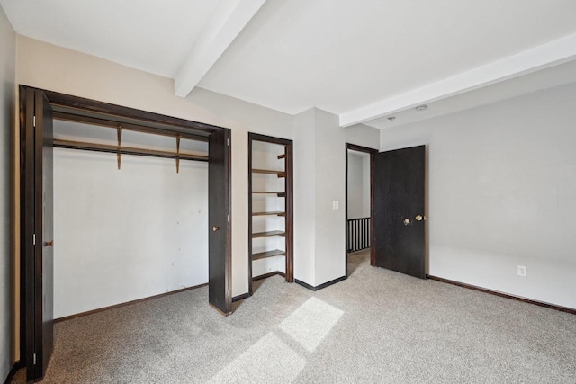 unfurnished bedroom featuring beam ceiling, light colored carpet, a closet, and baseboards