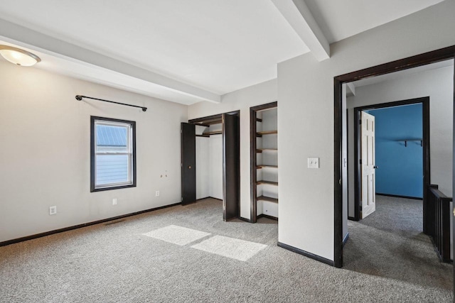 unfurnished bedroom featuring beamed ceiling, baseboards, and carpet