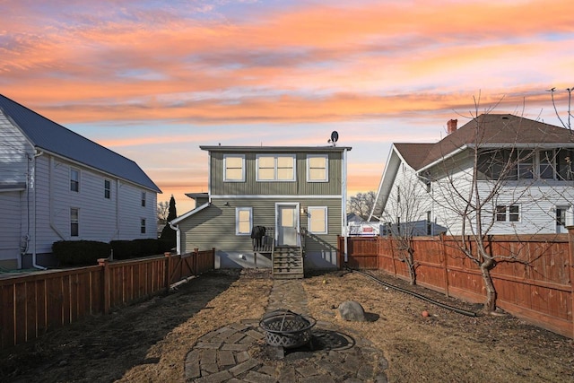 back of property featuring entry steps, a fenced backyard, and an outdoor fire pit