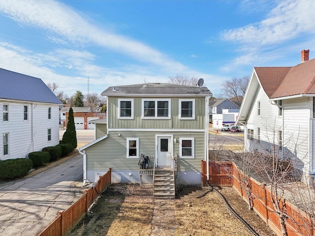 back of house featuring board and batten siding and fence