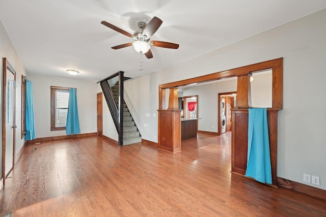 unfurnished room with stairway, baseboards, wood finished floors, and a ceiling fan