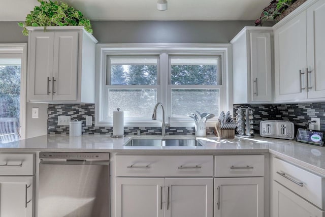 kitchen with a sink, dishwasher, white cabinets, and light countertops