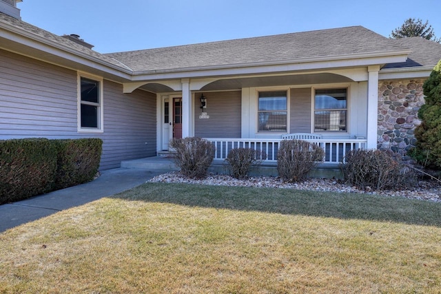 property entrance with covered porch, a lawn, stone siding, and a shingled roof