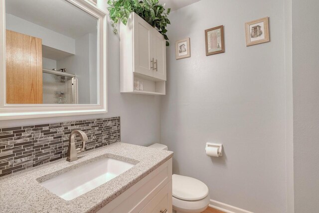 bathroom featuring vanity, a shower stall, toilet, and tasteful backsplash