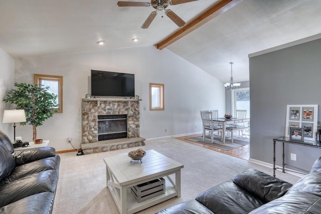 carpeted living room featuring baseboards, a stone fireplace, vaulted ceiling with beams, and ceiling fan with notable chandelier