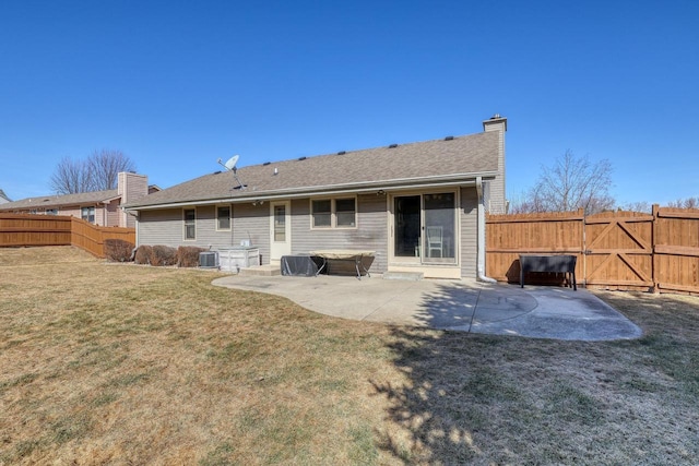 back of property featuring fence, cooling unit, a chimney, a yard, and a patio