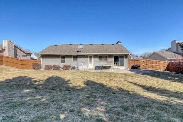 rear view of property featuring a fenced backyard, a lawn, a patio, and roof with shingles