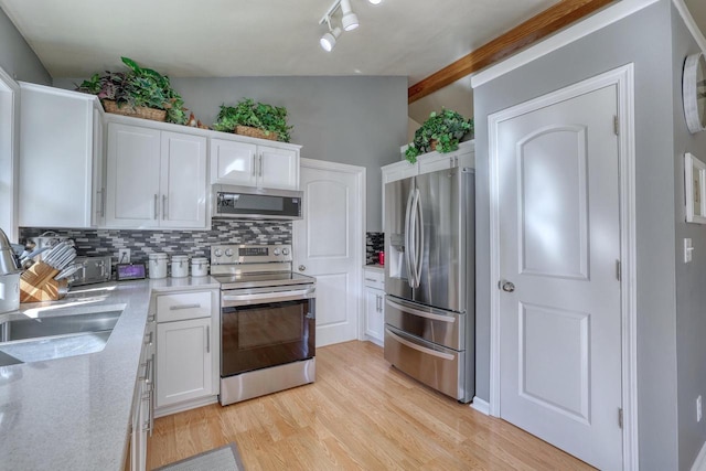 kitchen featuring white cabinetry, decorative backsplash, vaulted ceiling with beams, and appliances with stainless steel finishes