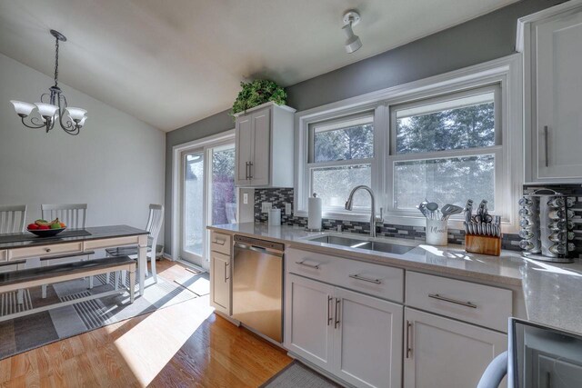 kitchen with light wood-type flooring, a sink, tasteful backsplash, lofted ceiling, and dishwasher