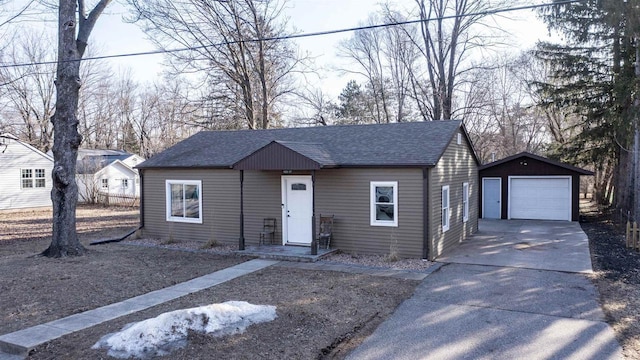 view of front of property featuring driveway, a detached garage, an outdoor structure, and roof with shingles