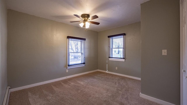 carpeted spare room with a baseboard heating unit, a ceiling fan, and baseboards