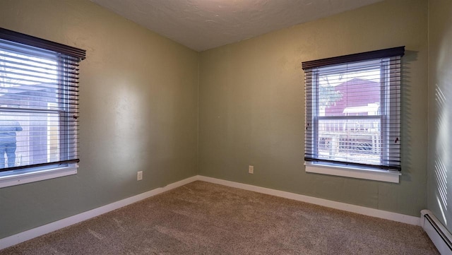 carpeted spare room with a wealth of natural light, baseboard heating, and baseboards