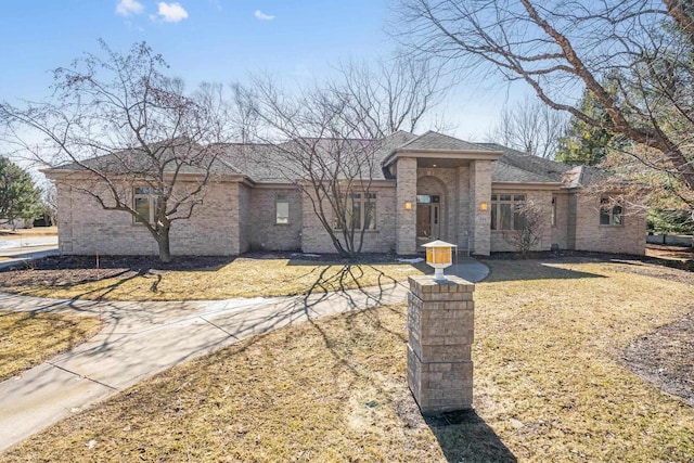 view of front of property with a front yard, brick siding, and a shingled roof