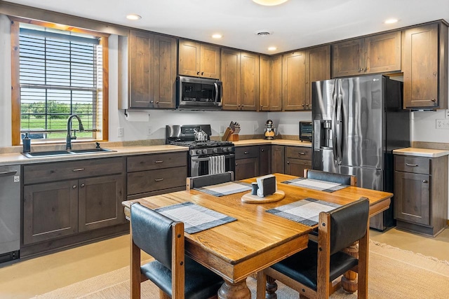 kitchen with a sink, recessed lighting, dark brown cabinetry, appliances with stainless steel finishes, and light countertops