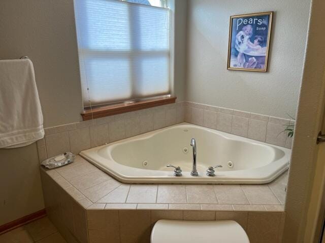 full bathroom featuring a wealth of natural light, toilet, a tub with jets, and tile patterned floors