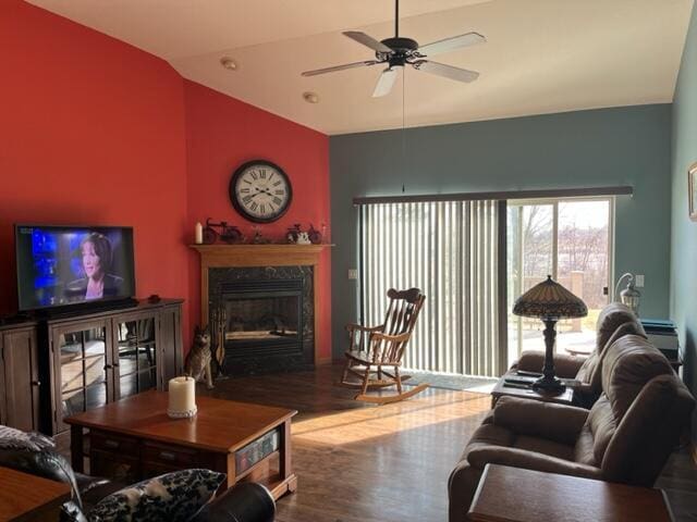 living area with a high end fireplace, wood finished floors, a ceiling fan, and vaulted ceiling