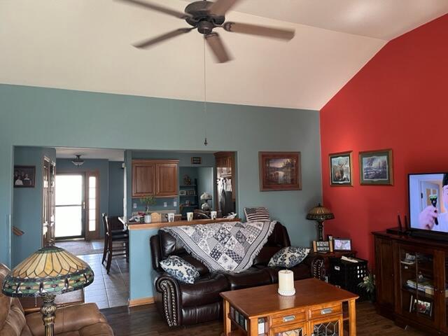 living area with lofted ceiling, dark wood-style floors, and ceiling fan