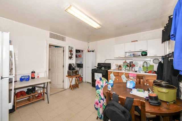 kitchen with visible vents, a sink, freestanding refrigerator, light countertops, and black range with gas stovetop