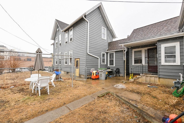 rear view of property with roof with shingles and fence