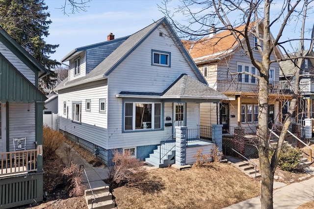 view of front of house featuring a porch, roof with shingles, and a chimney