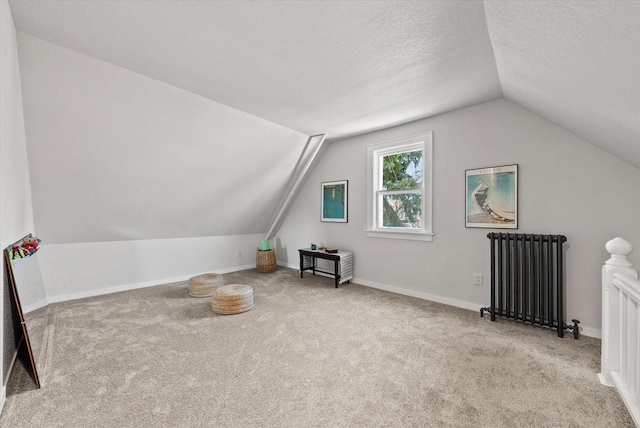 bonus room with a textured ceiling, radiator heating unit, carpet, baseboards, and vaulted ceiling