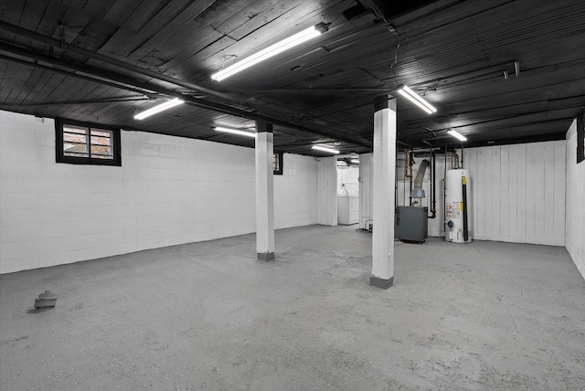 basement featuring gas water heater, washer / dryer, and concrete block wall