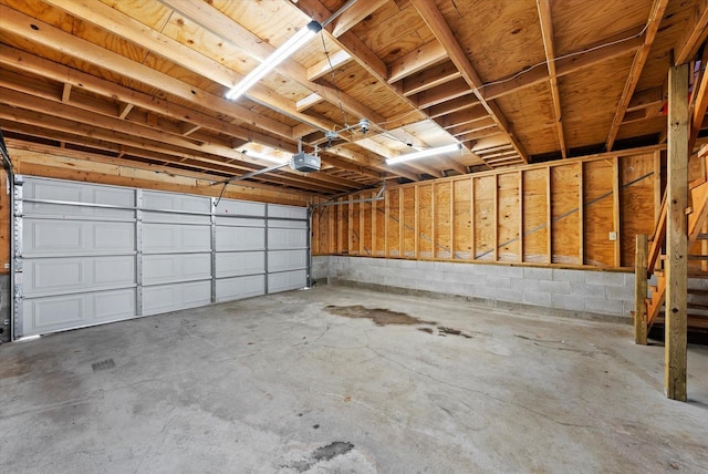 garage with a garage door opener and concrete block wall