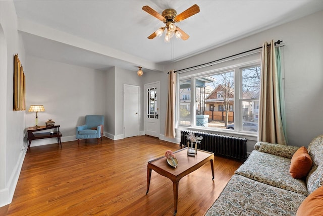 living room featuring ceiling fan, baseboards, radiator, and wood finished floors