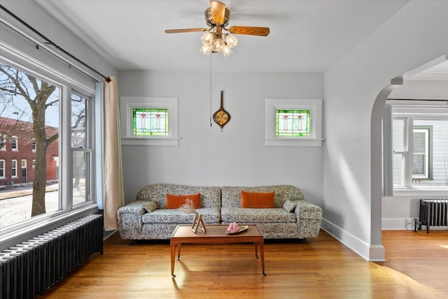 living room with arched walkways, radiator, and wood finished floors